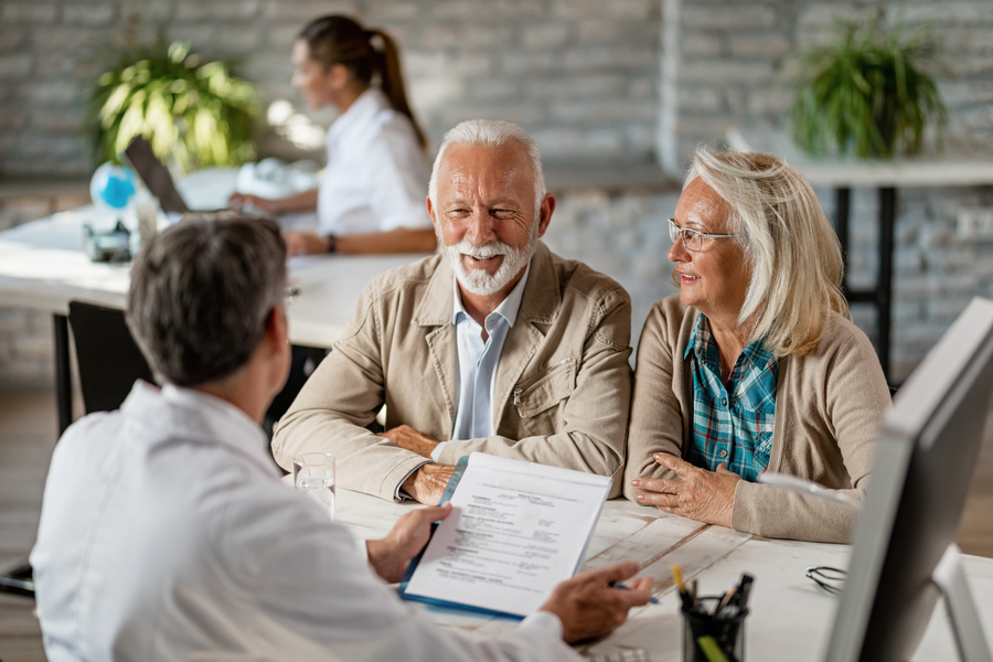 Happy senior couple communicating with a doctor about their medicare insurance while going through paperwork